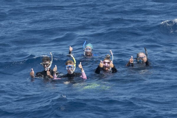 Snorkelers giving thumbs up above surface in open ocean water